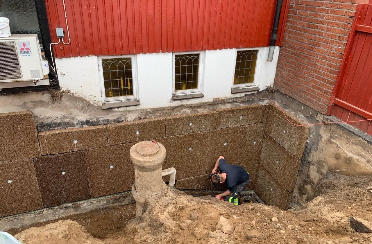 man som gör dränering på ett rött hus